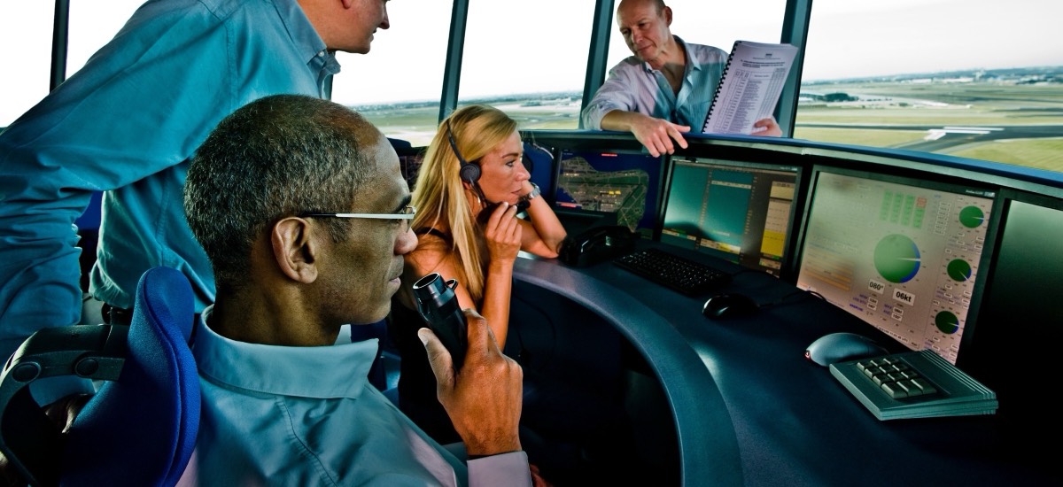 Controllers working an air traffic control tower with surveillance displays