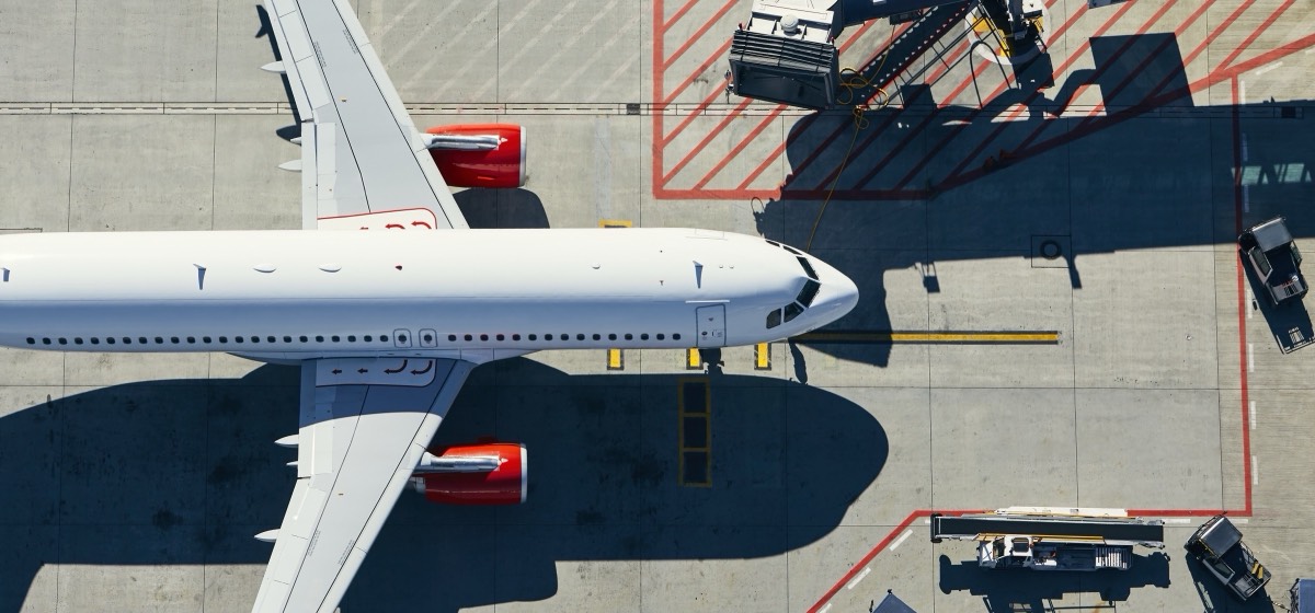 Aircraft at a stand seen from above, with apron markings and jet bridge