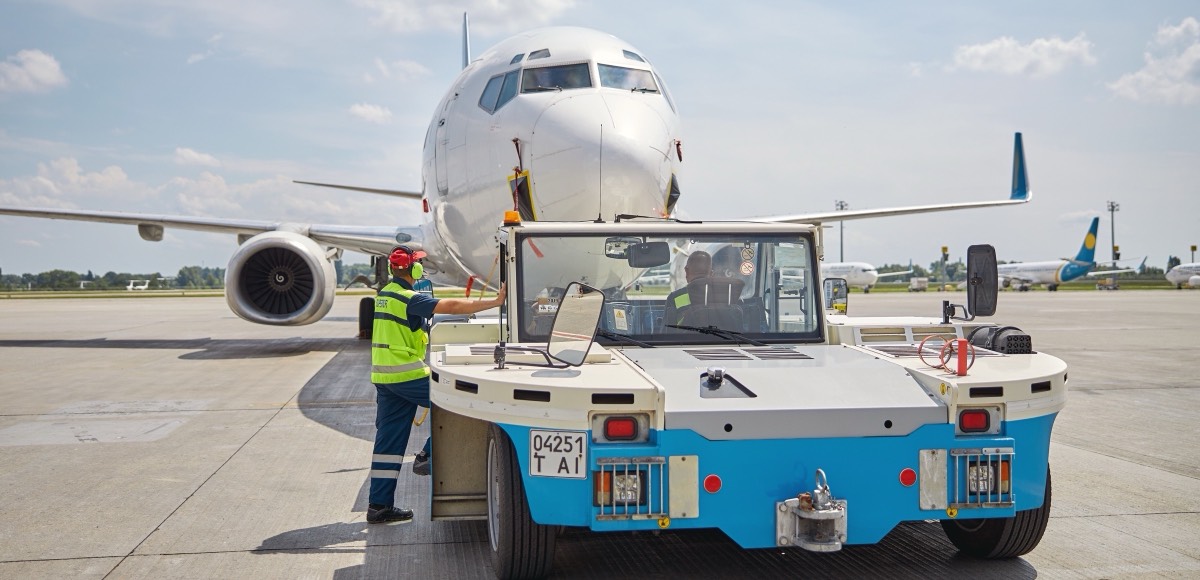 Ground crew and pushback tug at an aircraft stand
